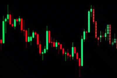 Un gráfico de velas japonesas en verde y rojo resalta sobre un fondo negro, mostrando las fluctuaciones de precio en un mercado financiero.