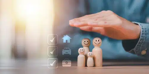 Una mano se extiende sobre figuras de madera de una familia para protegerlas, con íconos de seguro de hogar, vehículo y salud al lado.